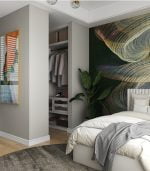 Yatak odasında, gri bir battaniye, soyut duvar sanatı ve iç mimar havası için büyük bir yeşil bitkiyle Basic yatak sergileniyor. Açık bir dolapta giysiler ve dekoratif kutular sergileniyor. Ahşap zeminde yuvarlak yeşil bir halı bulunuyor ve çerçeveli sanat eserleri tavan ışıklarının altındaki duvarları süslüyor.