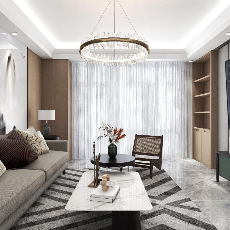 Gri bir kanepe, yuvarlak sehpa ve berjer bulunan modern oturma odası. Altında geometrik bir halı var. Üstünde dairesel bir avize asılı. İnce perdeler büyük bir pencereyi kapatarak villanın cazibesini artırıyor. Raflardaki dekor iç mimarın zarif vizyonunu tamamlıyor.